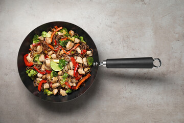 Stir-fry. Tasty noodles with meat and vegetables in wok on grey textured table, top view