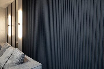 Modern living room interior with grey wooden slats and ice lamps on the wall.