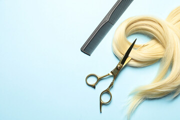 Professional hairdresser scissors and comb with blonde hair strand on light blue background, flat...