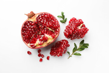Cut fresh pomegranate and green leaves on white background, flat lay