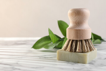 One cleaning brush and bar of soap on white marble table, closeup. Space for text