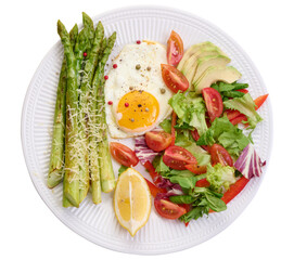 Round plate with cooked asparagus, fried egg, avocado and fresh vegetable salad