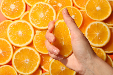 Woman squeezing juicy orange near slices of fruit, top view