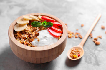 Tasty granola in bowl served on gray table, closeup