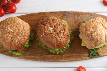 Delicious vegetarian burgers served on white wooden table, top view