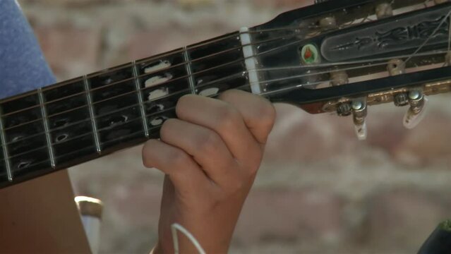 Hands of A Woman Tuning an Old Guitar Outdoors. Close Up.