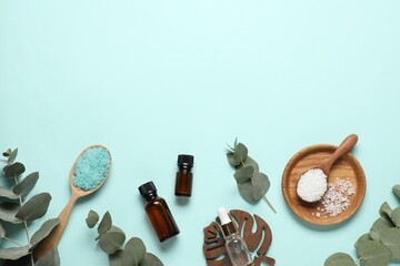 Aromatherapy products. Bottles of essential oil, sea salt and eucalyptus branches on light blue background, flat lay. Space for text