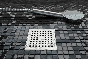 water drops on chrome shower drain next to the laying shower head. 3D Rendering