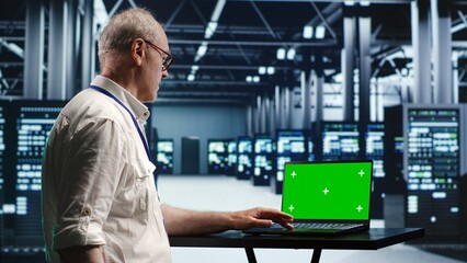 Fototapeta premium Developer in server room expertly managing data while navigating through industrial mainframes. Expert ensuring flawless cybersecurity guard, optimizing systems using green screen laptop