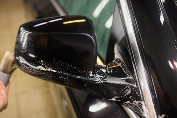 A person is cleaning a car windshield with a brush and water