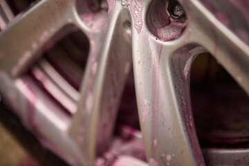 Closeup of automotive tire with water drops on rim and spokes