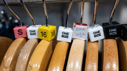 Wooden clothes hangers with coloured size cubes including one size in a retail fashion shop