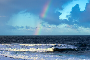 2023-02-03 A RAINBOW OVER THE SHORELINE IN LA JOLLA CALIFORNIA WITH A CLOUDY SKY AND WAVES COMING ONTO THE BEACH NEAR SAN DIEGO CALIFORNIA 