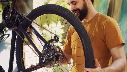 Energetic fit caucasian man outside repairing and maintaining bicycle components using specific...
