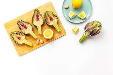 Fresh raw artichokes with lemon and garlic ready for cooking