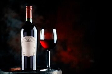 Glass of red wine and bottle of wine in old wooden barrel