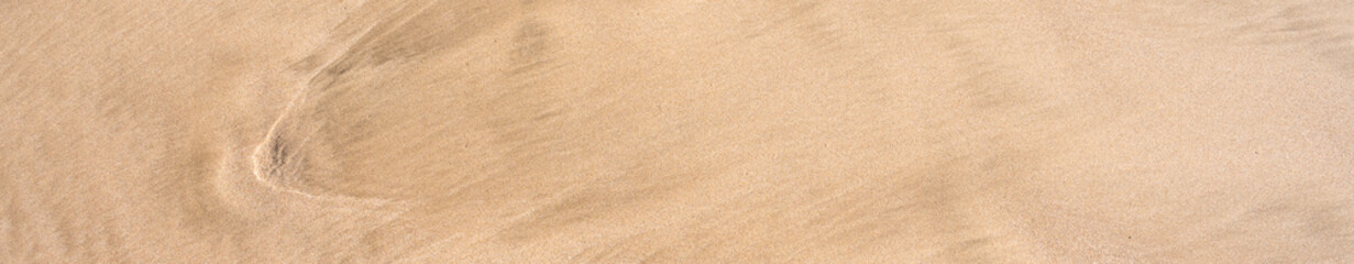 Clean golden sand with wave patterns, as a tropical nature beach background
