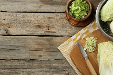 Fresh Chinese cabbages and knife on wooden table, top view. Space for text