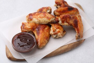 Board with marinade and chicken wings on light table, closeup