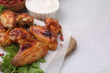 Fresh marinated chicken wings, spices and lettuce on light table, closeup. Space for text