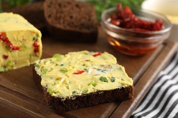 Tasty butter with green onion, chili pepper and rye bread on table, closeup