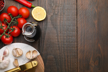 Different fresh ingredients for marinade and garlic press on wooden table, flat lay. Space for text
