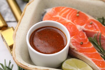 Fresh marinade, fish and lime in baking dish on table, closeup