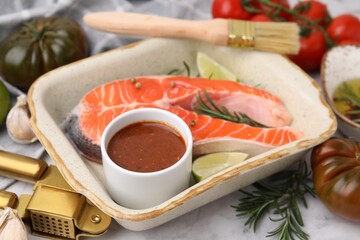 Fresh marinade, fish, lime, rosemary in baking dish and other products on table, closeup