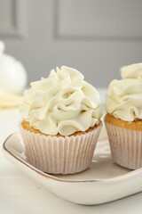 Tasty cupcakes with vanilla cream on white wooden table, closeup