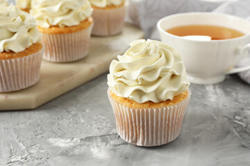 Tasty cupcakes with vanilla cream on grey table, closeup