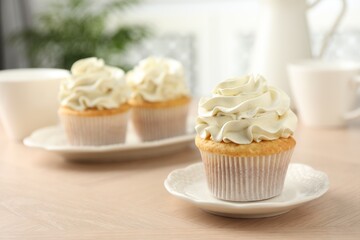Tasty cupcakes with vanilla cream on light wooden table, closeup
