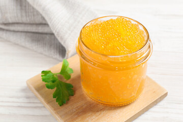 Fresh pike caviar in glass jar and parsley on white wooden table, closeup