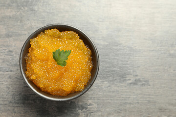 Fresh pike caviar and parsley in bowl on grey table, top view. Space for text