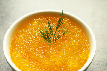 Fresh pike caviar and dill in bowl on grey table, closeup