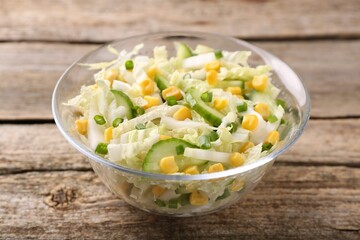 Tasty salad with Chinese cabbage, corn and cucumber in bowl on wooden table, closeup