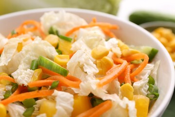 Tasty salad with Chinese cabbage, carrot, corn and cucumber in bowl on table, closeup