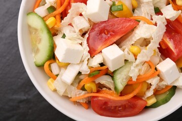 Tasty salad with Chinese cabbage, carrot, cheese, cucumber, corn and tomato on black table, top view