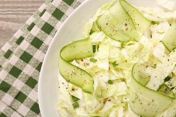 Tasty salad with Chinese cabbage, cucumber and green onion in bowl on wooden table, top view
