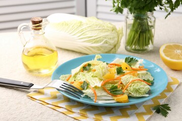 Tasty salad with Chinese cabbage, products and fork on beige table