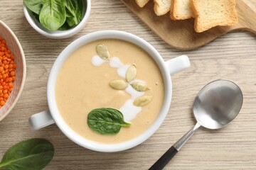 Healthy cream soup high in vegetable fats served on wooden table, flat lay