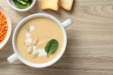 Healthy cream soup high in vegetable fats, bread and spinach on wooden table, flat lay. Space for text