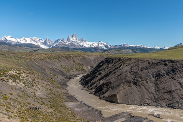 A river flows through a valley with Mount Fitz Roy in the background