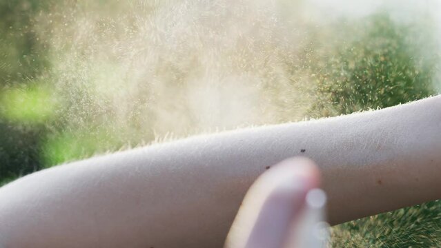 Slow motion of a person spraying arm with a tick prevention spray. Using an anti tick spray during the summer time to decrease the risk of tick bites. 