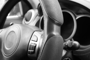 Car steering wheel close-up, black and white. Car dashboard