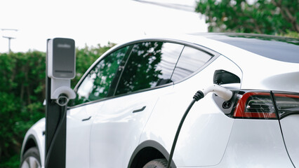 EV electric car recharge battery at parking lot in natural green city park. Alternative clean...