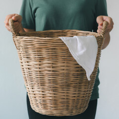 A cropped image of a beautiful young woman holding a laundry basket of clothes with a white background.