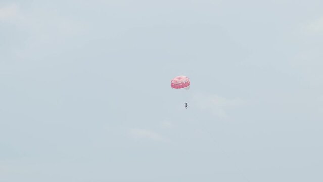 people on a parachute flying in the sky, on cable, slow motion
