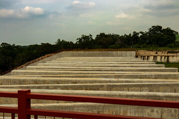 A series of concrete walls, integral to the design of a flood control structure. As the cloudy...