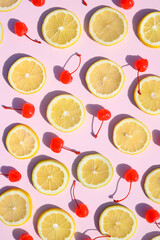 Sliced lemons and cherry fruit on a pink background. Summer aesthetic pattern. Strong visual concept.