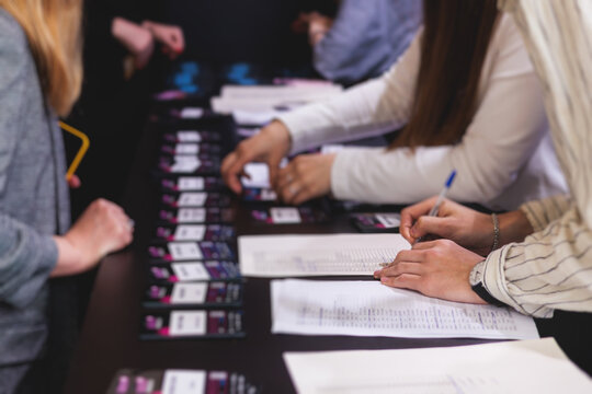 Process of checking in on a conference congress forum event, registration desk table, visitors and attendees receiving a name badge and entrance wristband bracelet and register electronic ticket